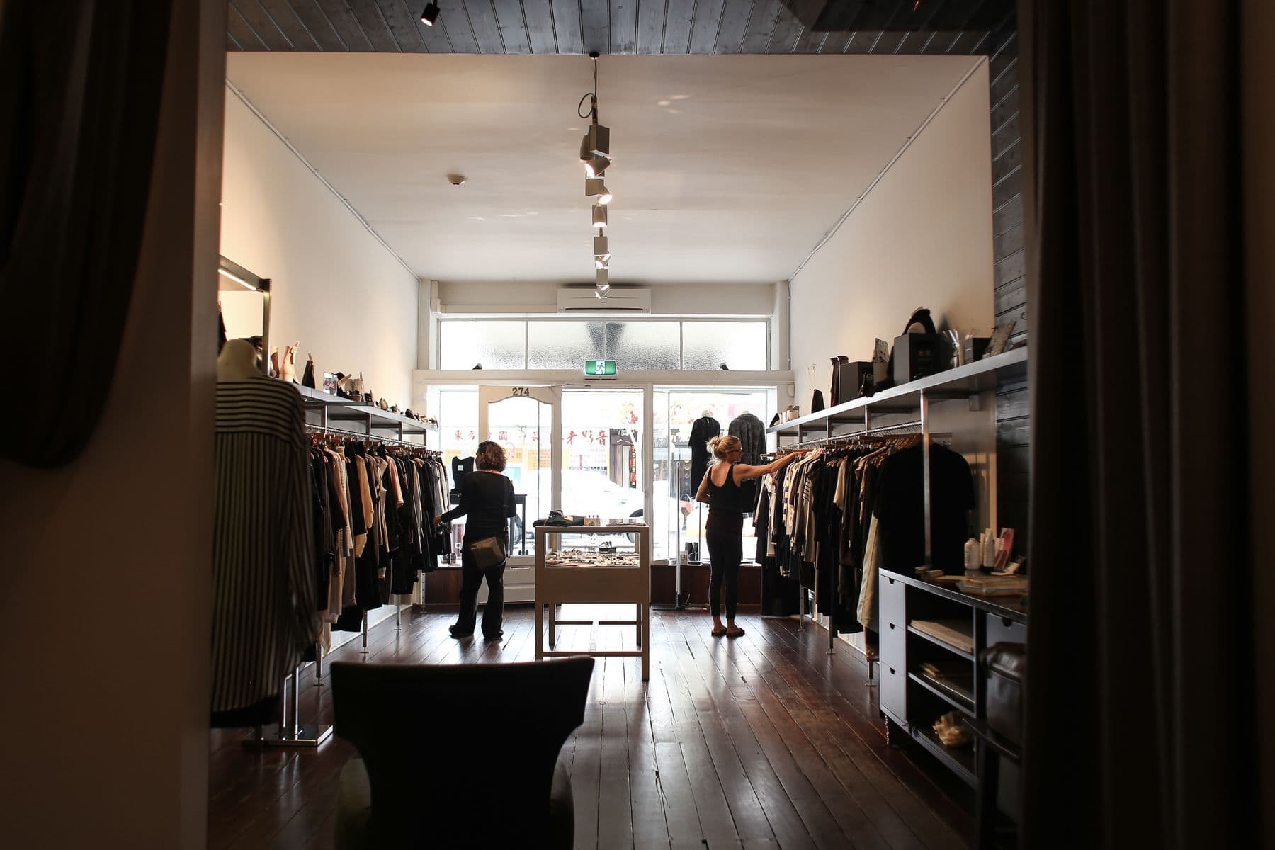 Interior de una tienda de ropa con la puerta a la calle al fondo